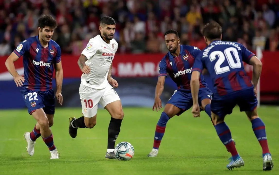 El centrocampista argentino del Sevilla, &Eacute;ver Banega, conduce el bal&oacute;n ante la presi&oacute;n de varios futbolistas del Levante. - efe