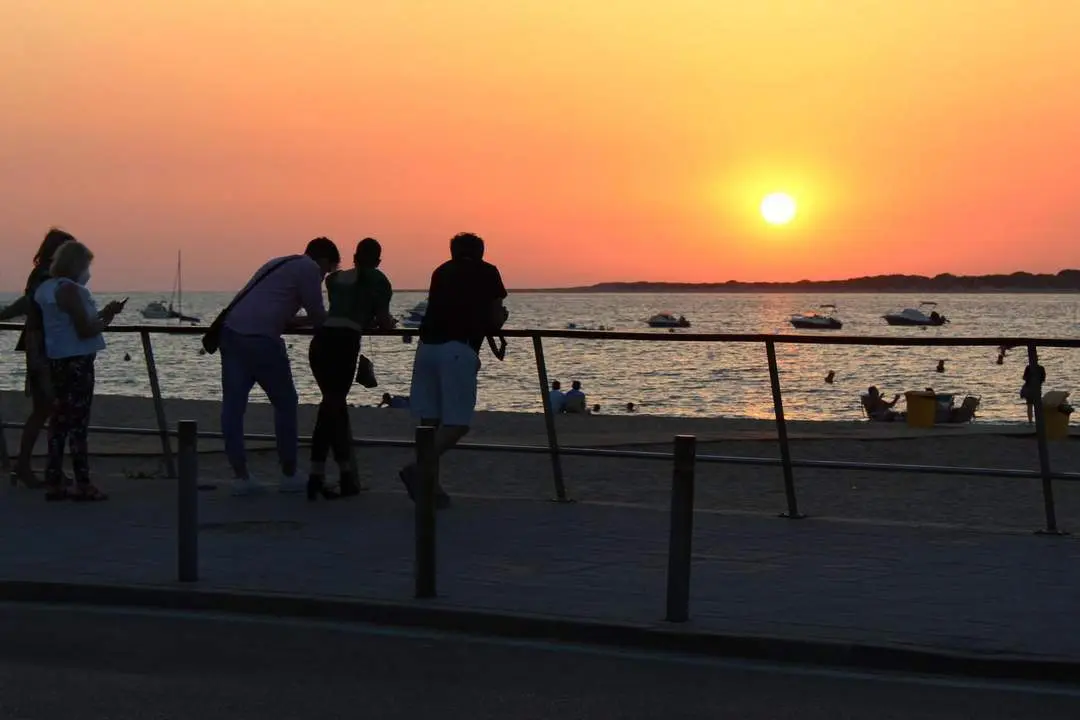 Varios visitantes contemplando el atardecer en el Paseo Mar&iacute;timo con Do&ntilde;ana al fondo - Ra&uacute;l J. Bustillos