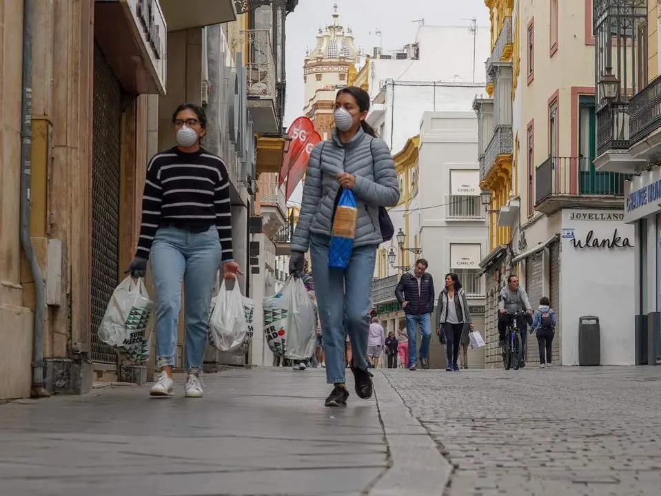 Dos personas con mascarillas por la calle Tetu&aacute;n de Sevilla. - ep