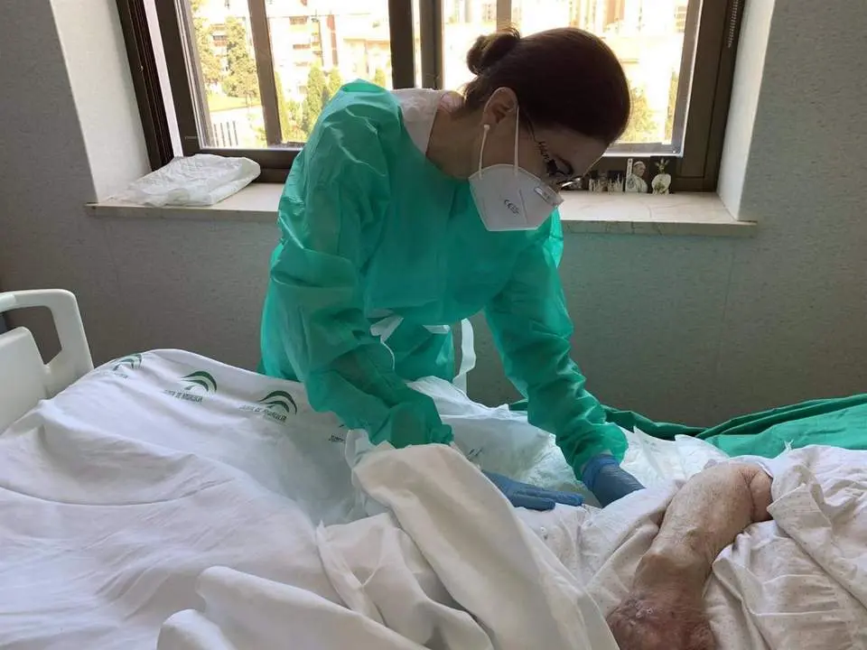 Una profesional sanitaria atiende a una persona ingresada en el hospital en M&aacute;laga - Junta
