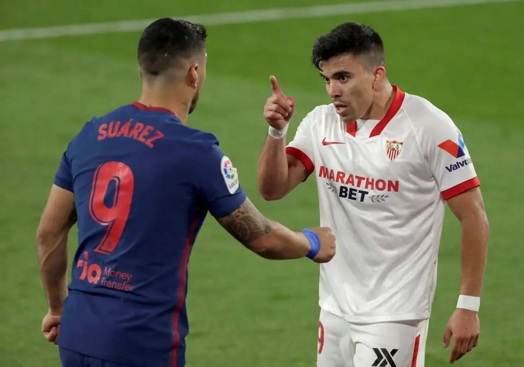 El lateral izquierdo del Sevilla, Marcos Acu&ntilde;a, discute con Luis Su&aacute;rez durante un partido contra el Atleti. - efe