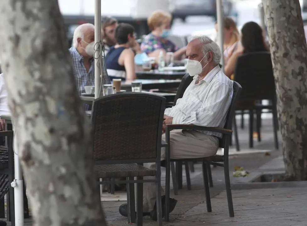 Personas con mascarillas en una terraza. - ep