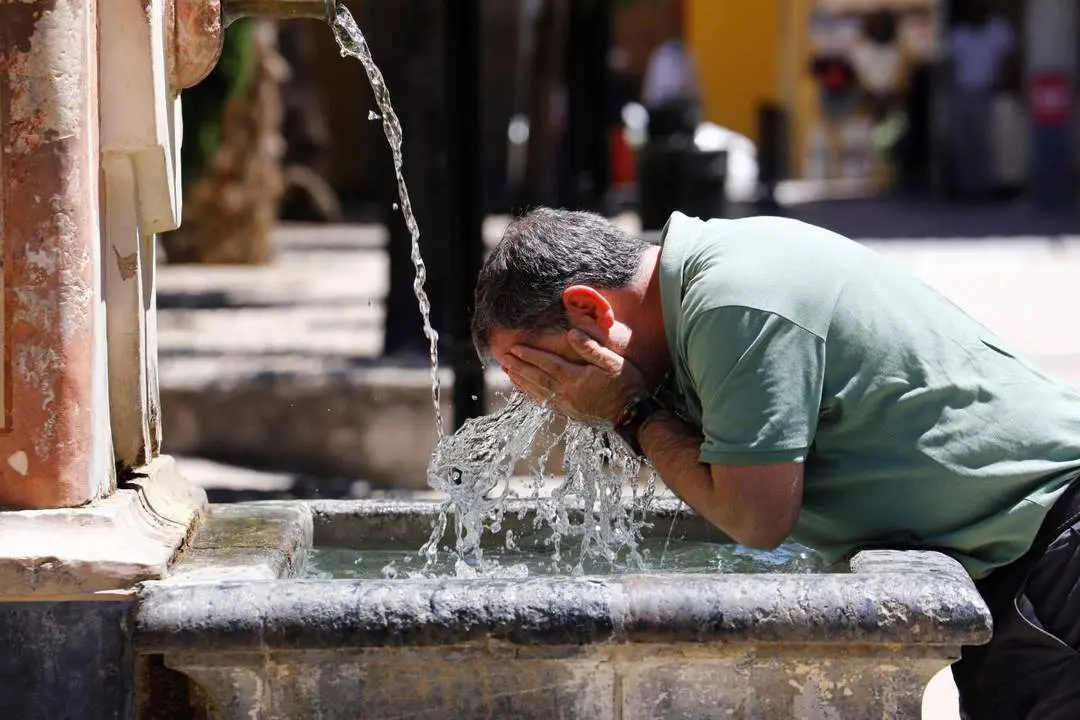 Un andaluz se refresca en una fuente de C&oacute;rdoba. - EFE