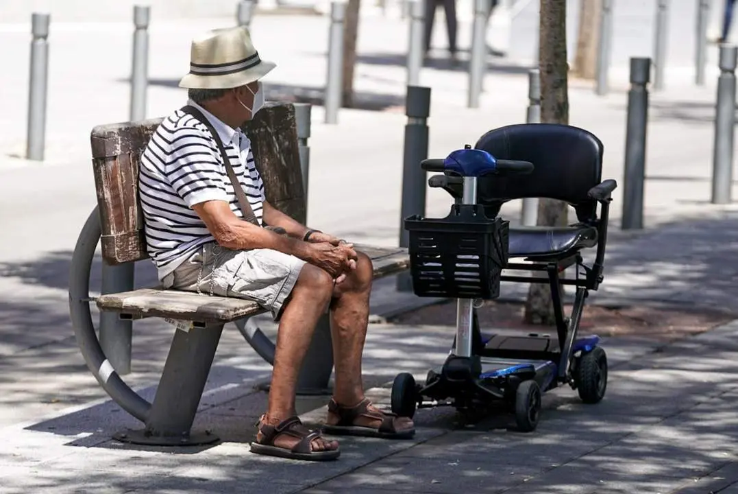 Un hombre con mascarilla sentado en un banco. - ep