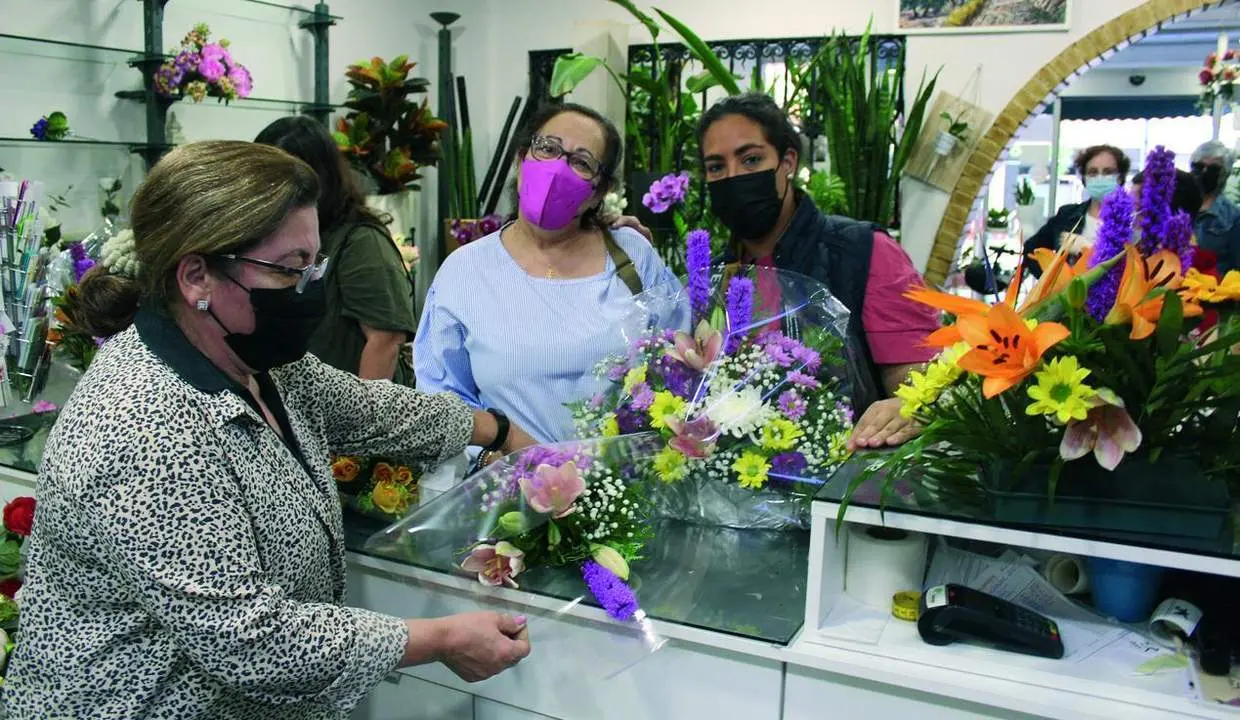 Antonia Exp&oacute;sito entregando el encargo a dos jiennenses en &lsquo;Florister&iacute;a Aguilera&rsquo;.   - Viva Ja&eacute;n.