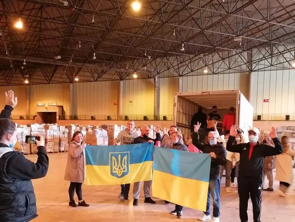 Voluntarios portan banderas de Ucrania tras cargar un cami&oacute;n con ayuda humanitaria. - CPalacios/EP