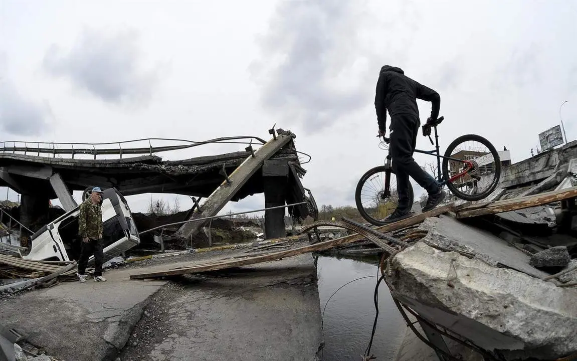 Un hombre cruza un puente derribado en Irpin. - efe