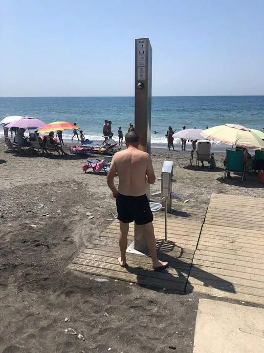 Un usuario de la playa de Algarrobo en una ducha de la playa, a 31 de julio. - Europa Press