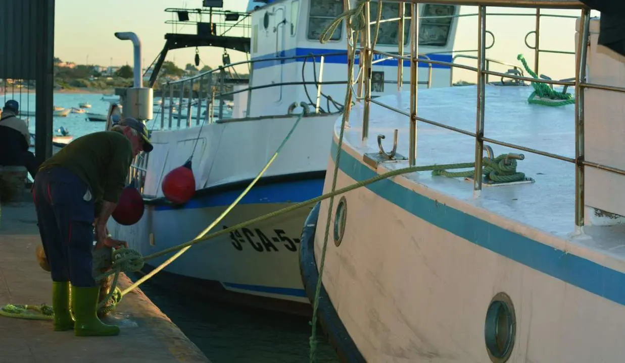 Un marinero amarrando un barco de arrastre en el puerto de Bonanza, en Sanl&uacute;car. - C. Cruz