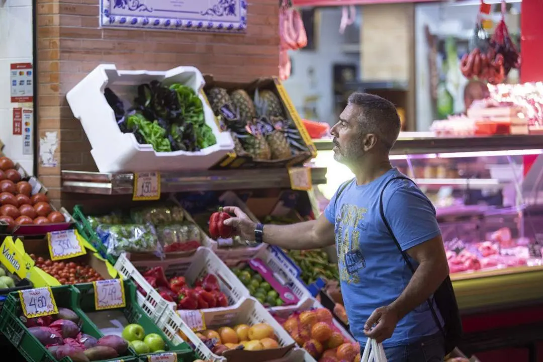 Un hombre comprando en un mercado de abastos de Triana. - Europa Press