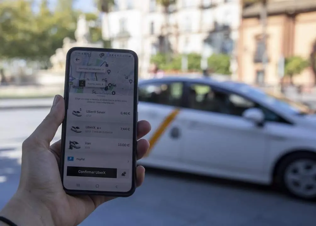 Imagen de un usuario con su tel&eacute;fono m&oacute;vil ante una parada de taxis. - EP