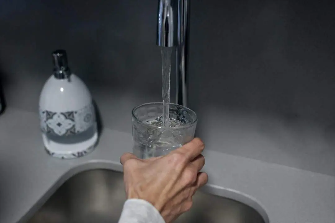 Una persona llena un vaso de agua de un grifo. - Viva Sevilla.