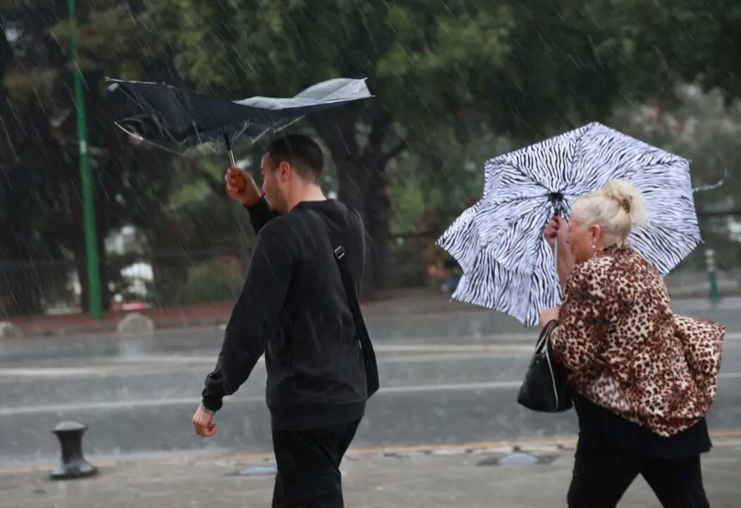 Sevillanos refugi&aacute;ndose de la lluvia y el viento. | Roc&iacute;o Ruz - Europa Press