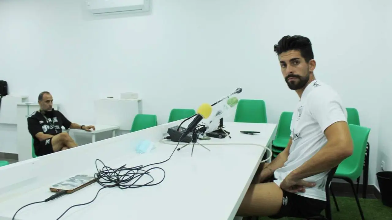 Isma Gil en la sala de prensa del Atl&eacute;tico Sanluque&ntilde;o y al fondo su entrenador, Romerito - Ra&uacute;l J. Bustillos