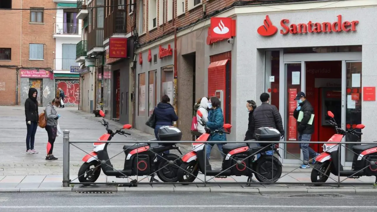 Varias personas esperan para entrar a una oficina del Banco Santander. - Europa Press