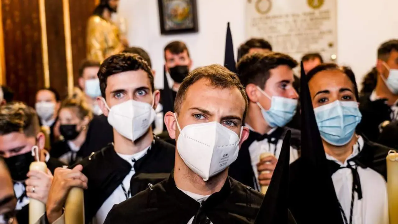 Nazarenos con mascarillas de la Hermandad de Santa Genoveva, en el interior del templo, en la Semana Santa de Sevilla. - EDUARDO BRIONES / EP 