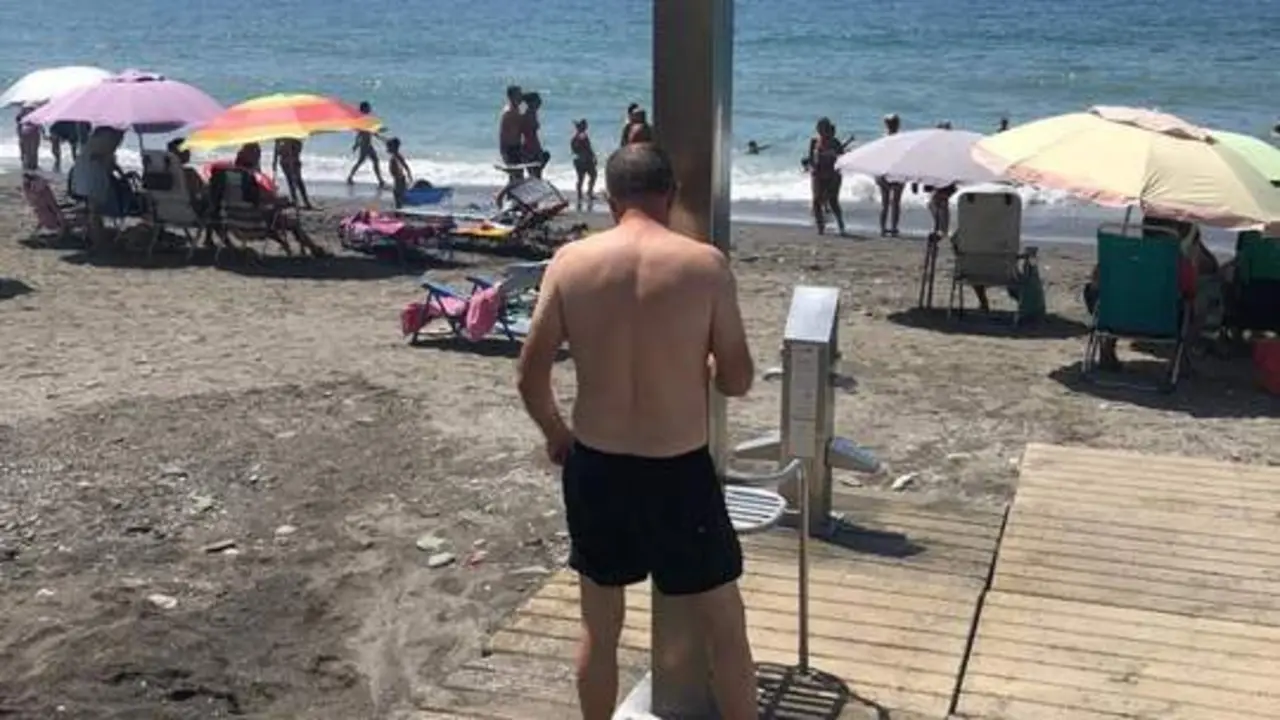 Un usuario de la playa de Algarrobo en una ducha de la playa, a 31 de julio. - Europa Press