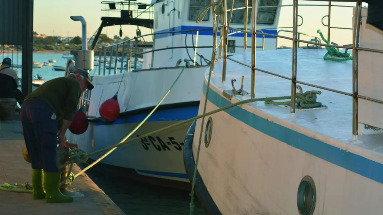 Un marinero amarrando un barco de arrastre en el puerto de Bonanza, en Sanl&uacute;car. - C. Cruz