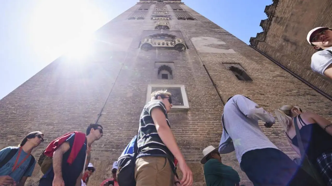 Un grupo de turistas junto a la Giralda de Sevilla. - Europa Press