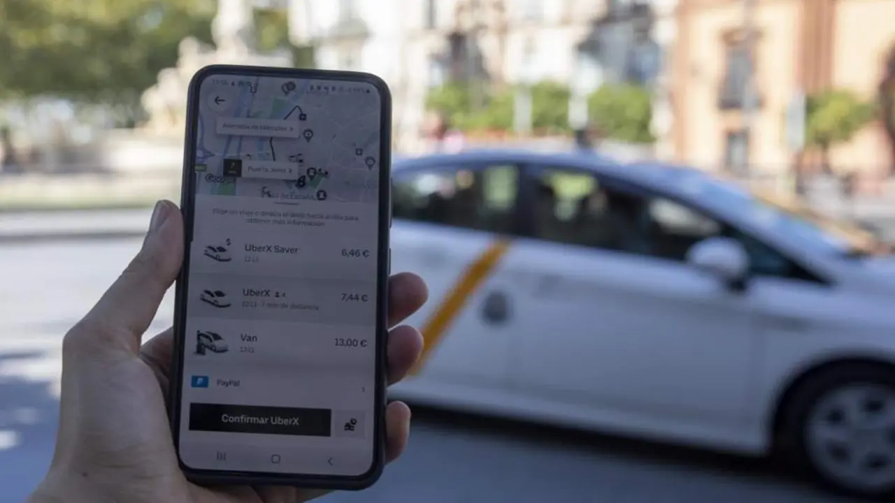 Imagen de un usuario con su tel&eacute;fono m&oacute;vil ante una parada de taxis. - EP