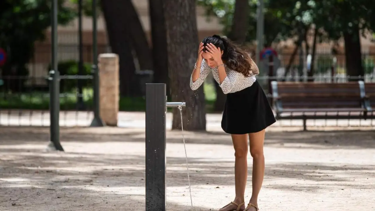Una mujer se refresca en una fuente. - Europa Press