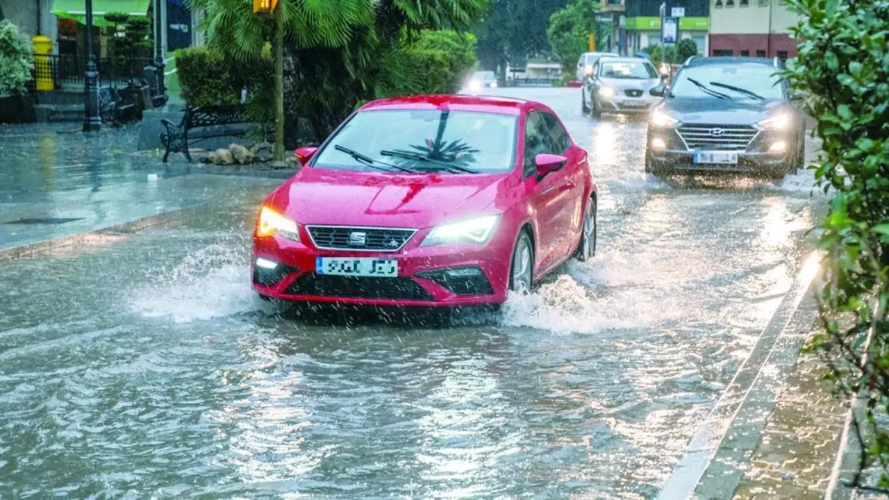 Veh&iacute;culos circulando por una calle medio inundada este jueves. - J. P&Eacute;REZ / EFE