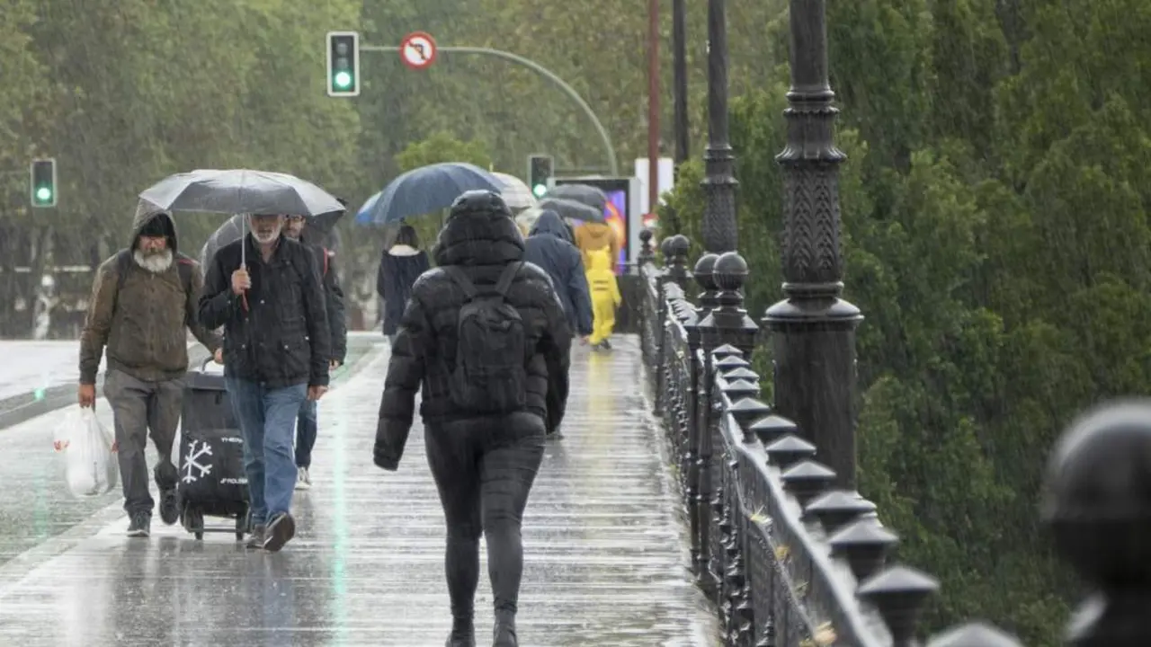 Peatones caminan bajo la lluvia en Sevilla. - EFE