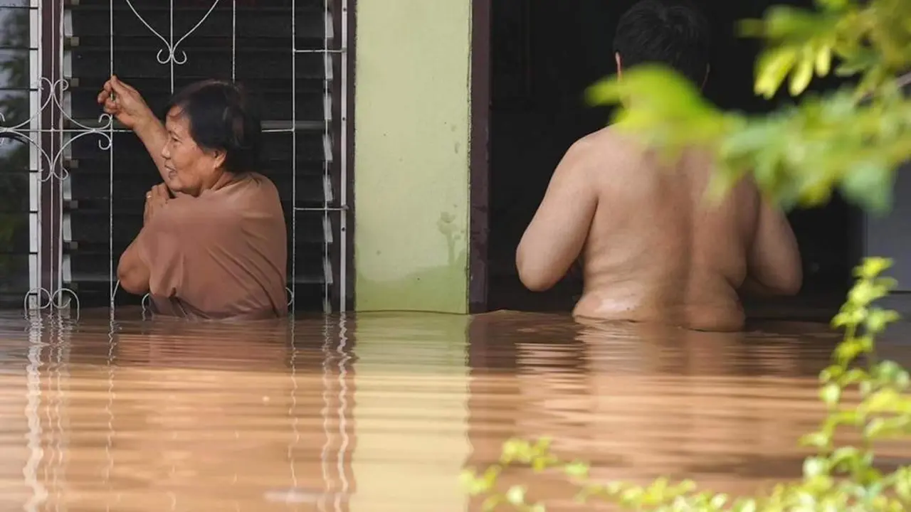 El agua cubre dos vecinos que intentan entrar en su casa. - EFE
