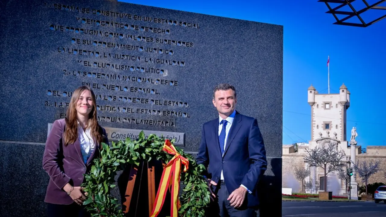 La estudiante Luna Catal&aacute;n y el alcalde, Bruno Garc&iacute;a, colocan una corona bajo la escultura que simboliza la Constituci&oacute;n, frente a las Puertas de Tierra. / VIVA
