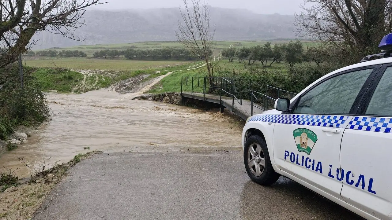 Veh&iacute;culo de la Polic&iacute;a Local ante un arroyo con el caudal crecido en Cuevas del Becerro durante la borrasca Leonardo a 4 de febrero de 2026. / AYTO. CUEVAS DEL BECERRO