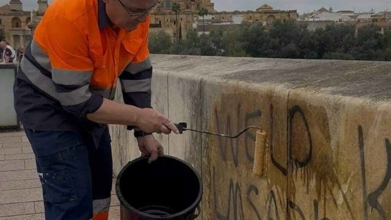 Equipo de limpieza de Sadeco ante las pintadas en el Puente Romano. | Europa Press.